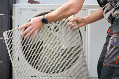 Technician removing cover from outdoor heat pump unit